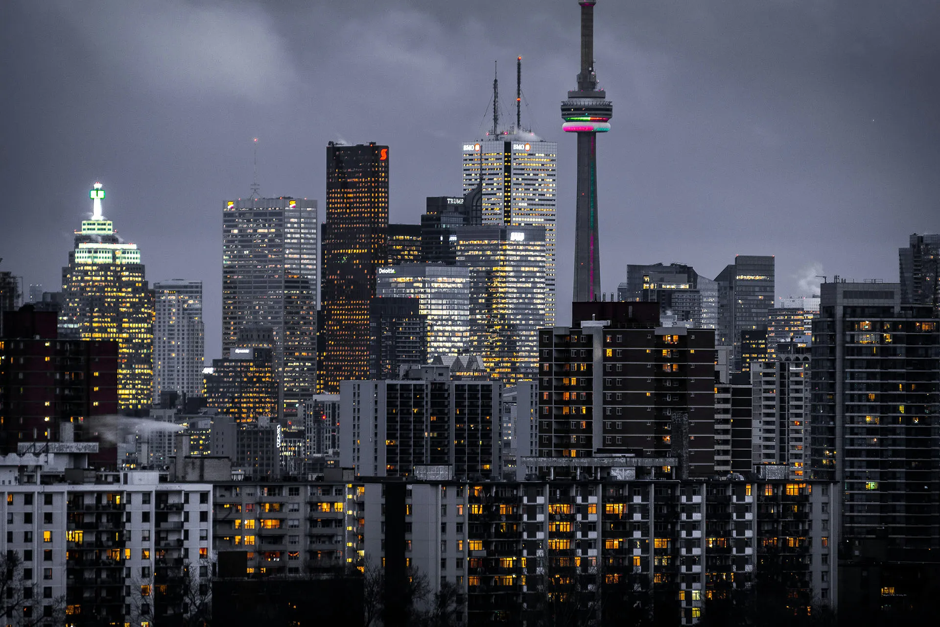  Toronto skyline at dusk featuring the CN Tower surrounded by high-rise buildings.