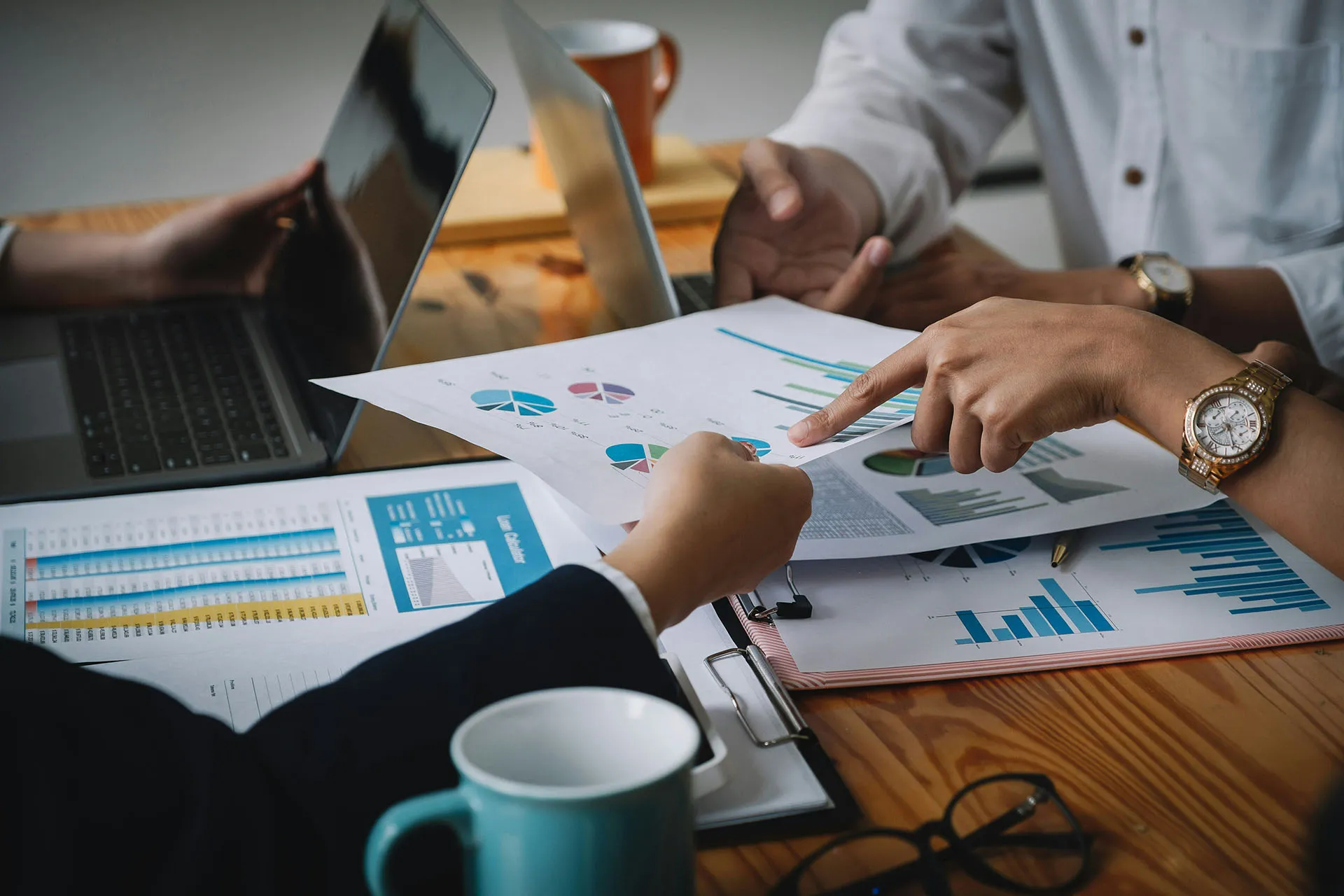  A team of financial professionals reviewing printed investment performance charts and data reports during a strategic portfolio management meeting.