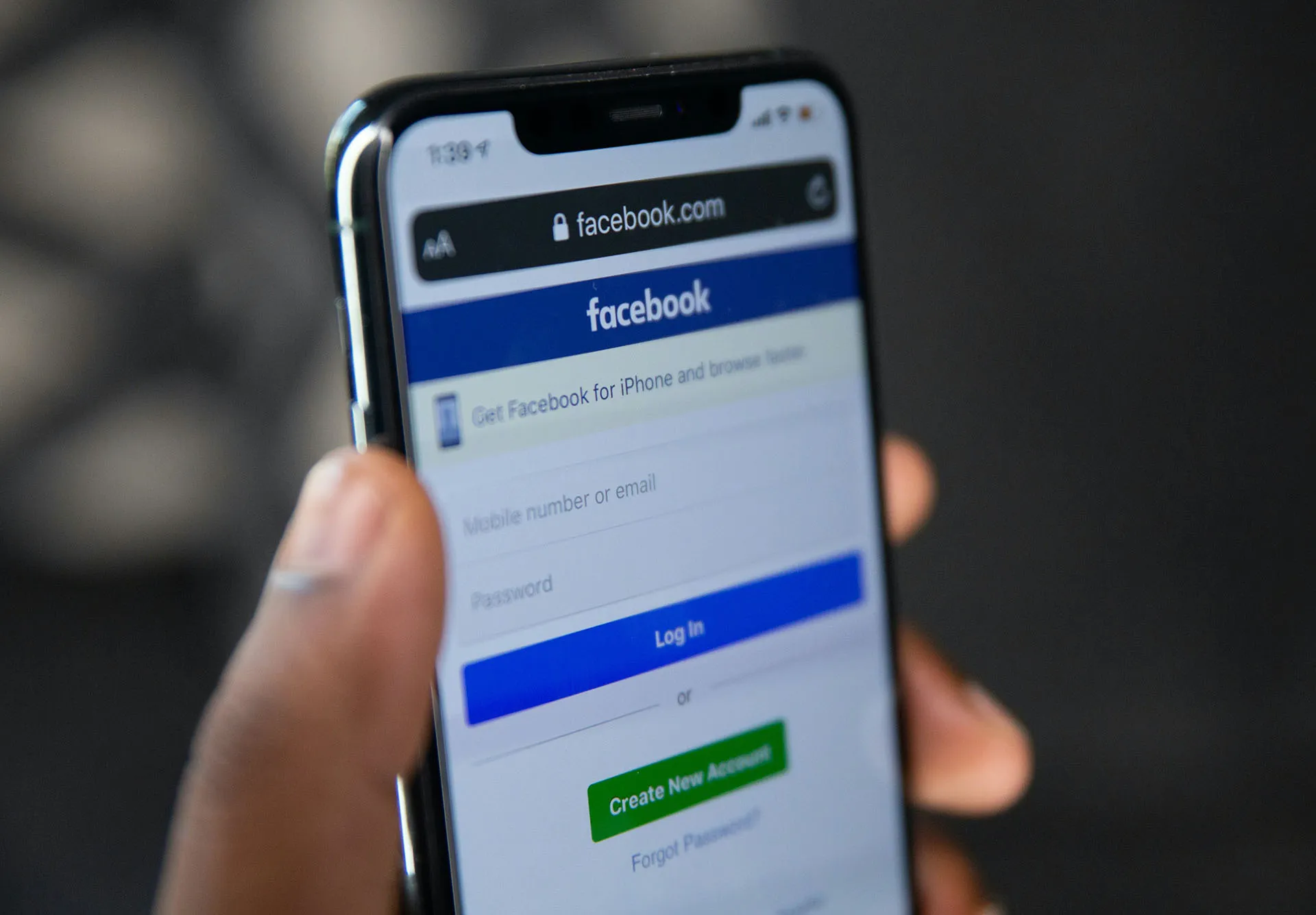  Hand holding a smartphone displaying the Facebook login screen