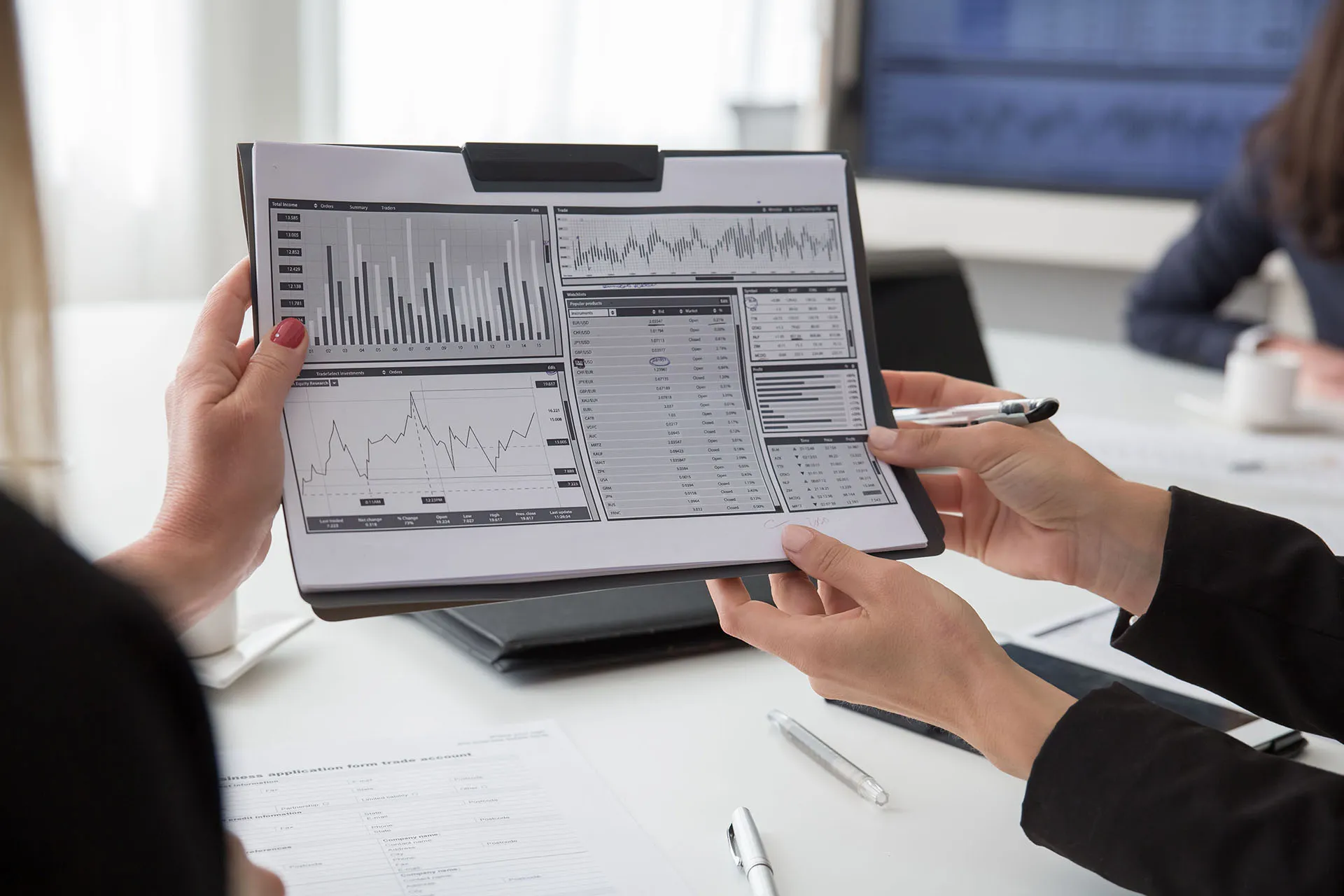  A close-up shot of financial advisors' hands pointing to data, pie charts, and bar graphs during a portfolio strategy meeting.