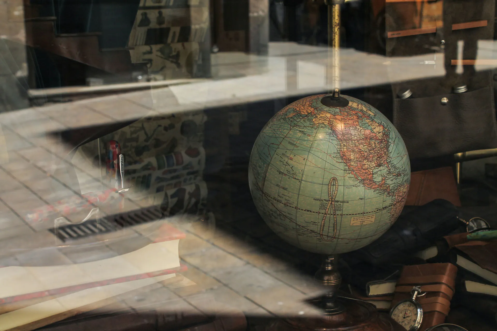 Vintage globe displayed behind a window with books and travel accessories, representing global business, travel, and international research.