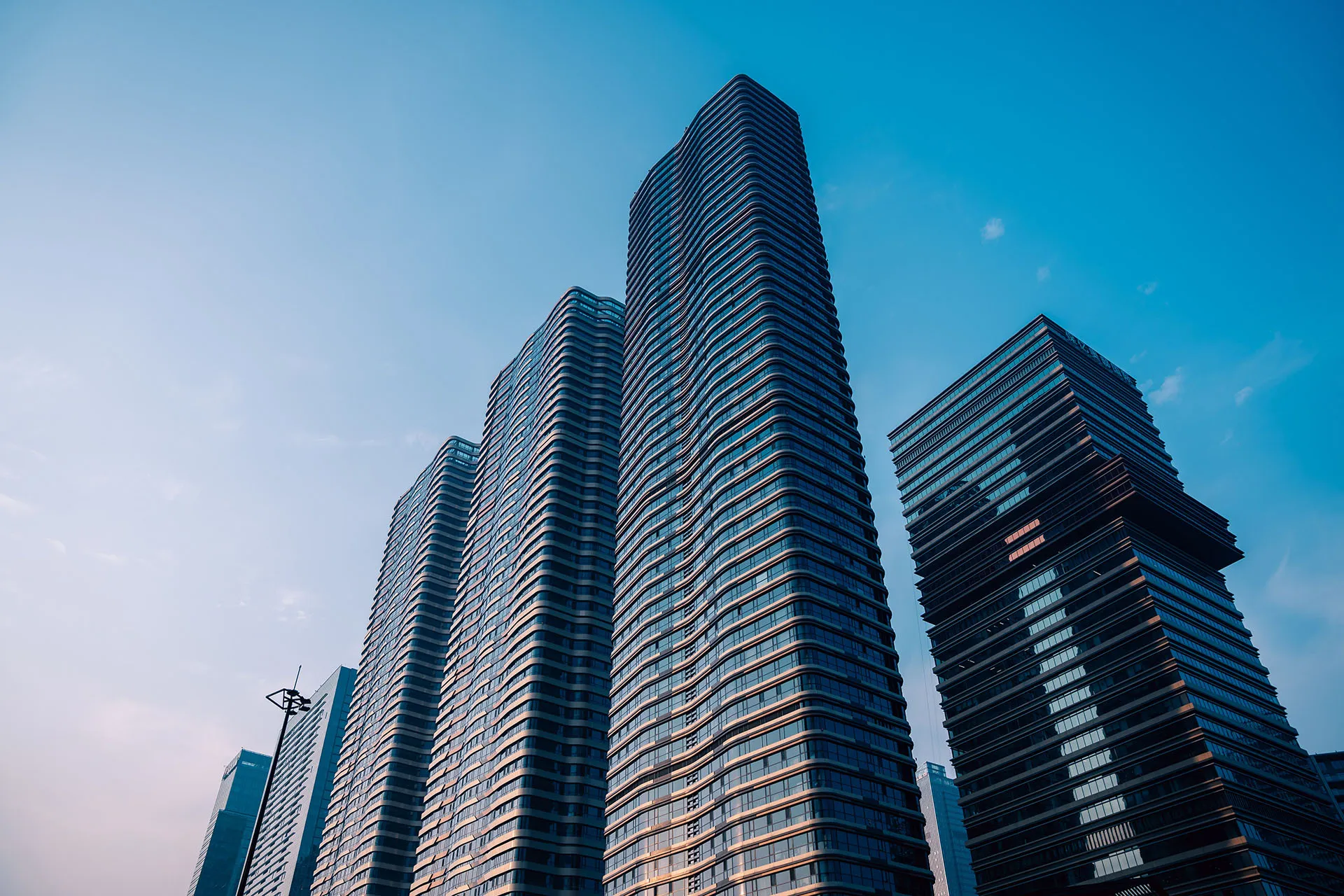 Modern apartment building with balconies and large windows against a bright blue sky.