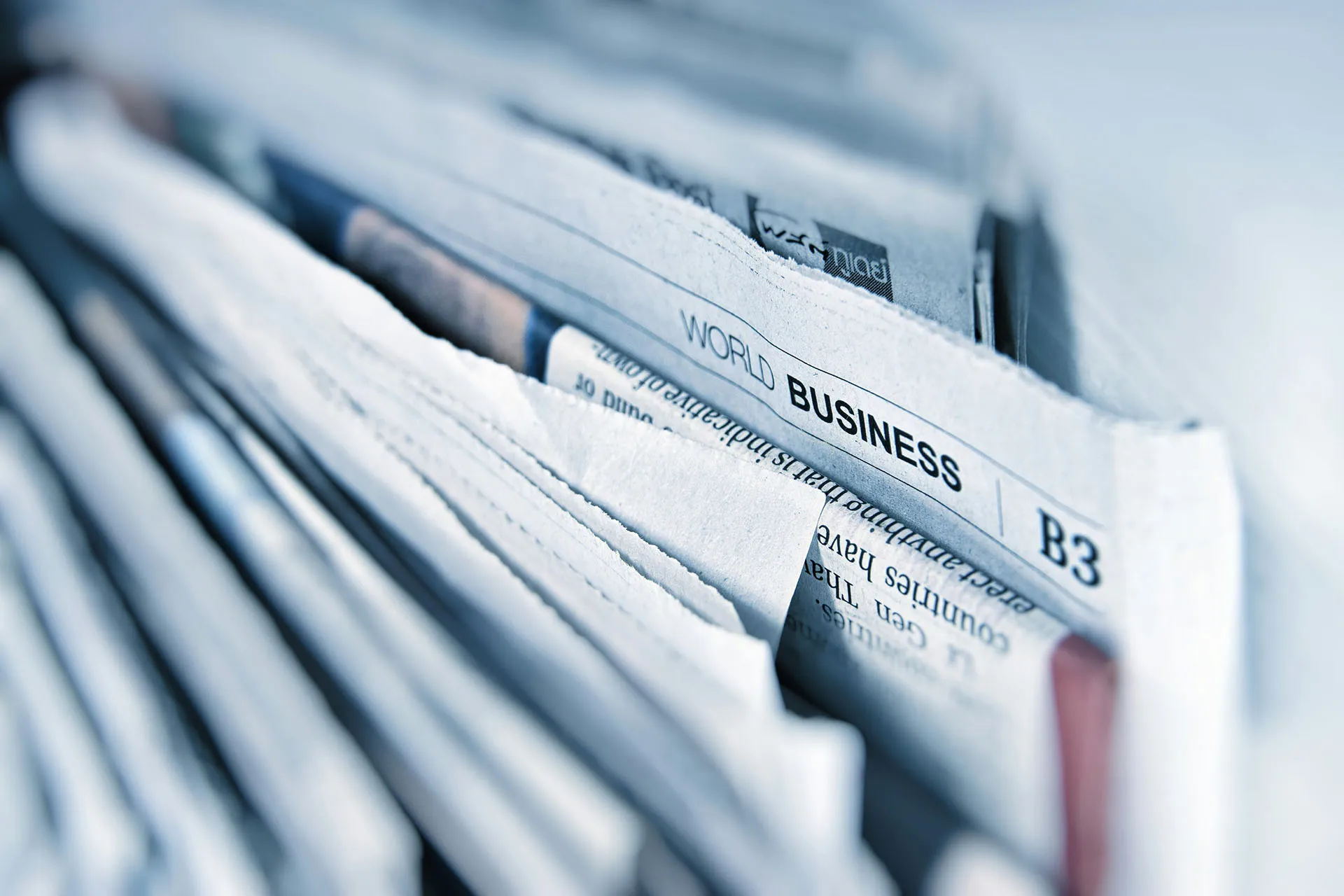 Close-up of folded newspapers with a visible world business section, representing financial news and print media.