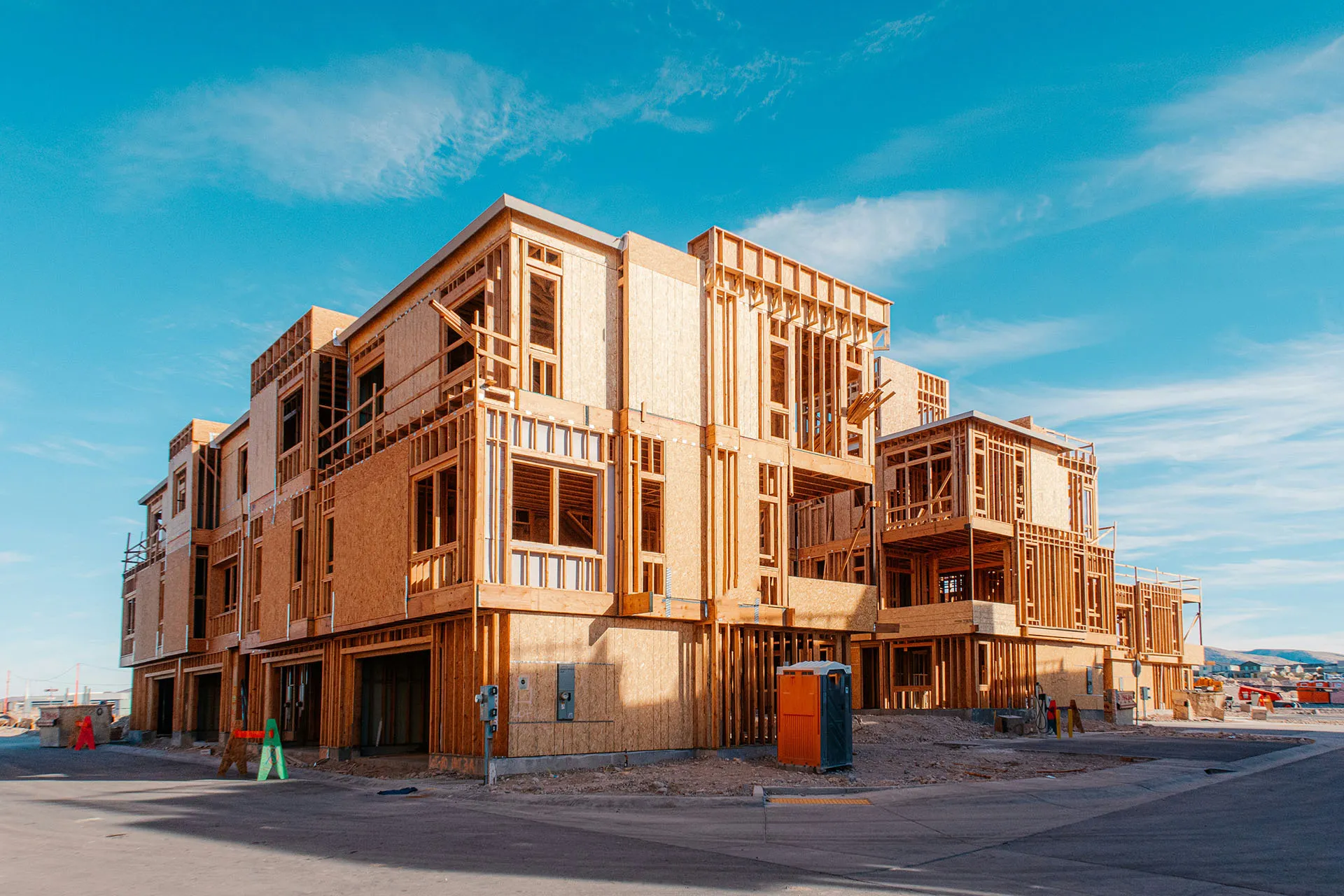  Multi-story building under construction with exposed wooden framing against a bright blue sky.