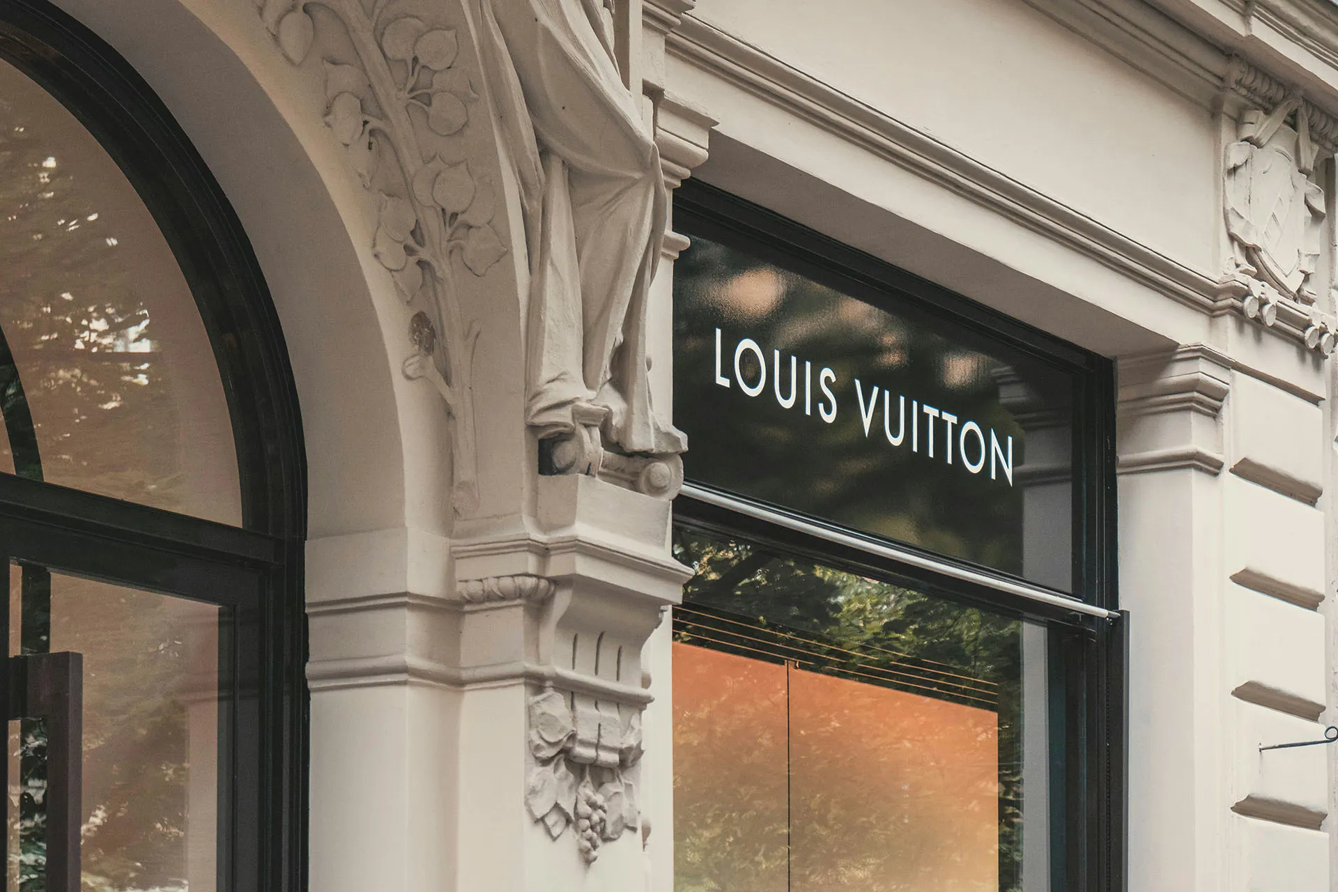  Louis Vuitton storefront with illuminated signage on an ornate building exterior.