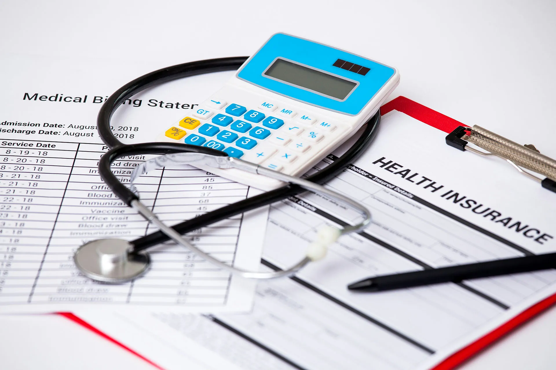 Medical billing documents with a stethoscope, calculator, pen, and health insurance form on a desk.