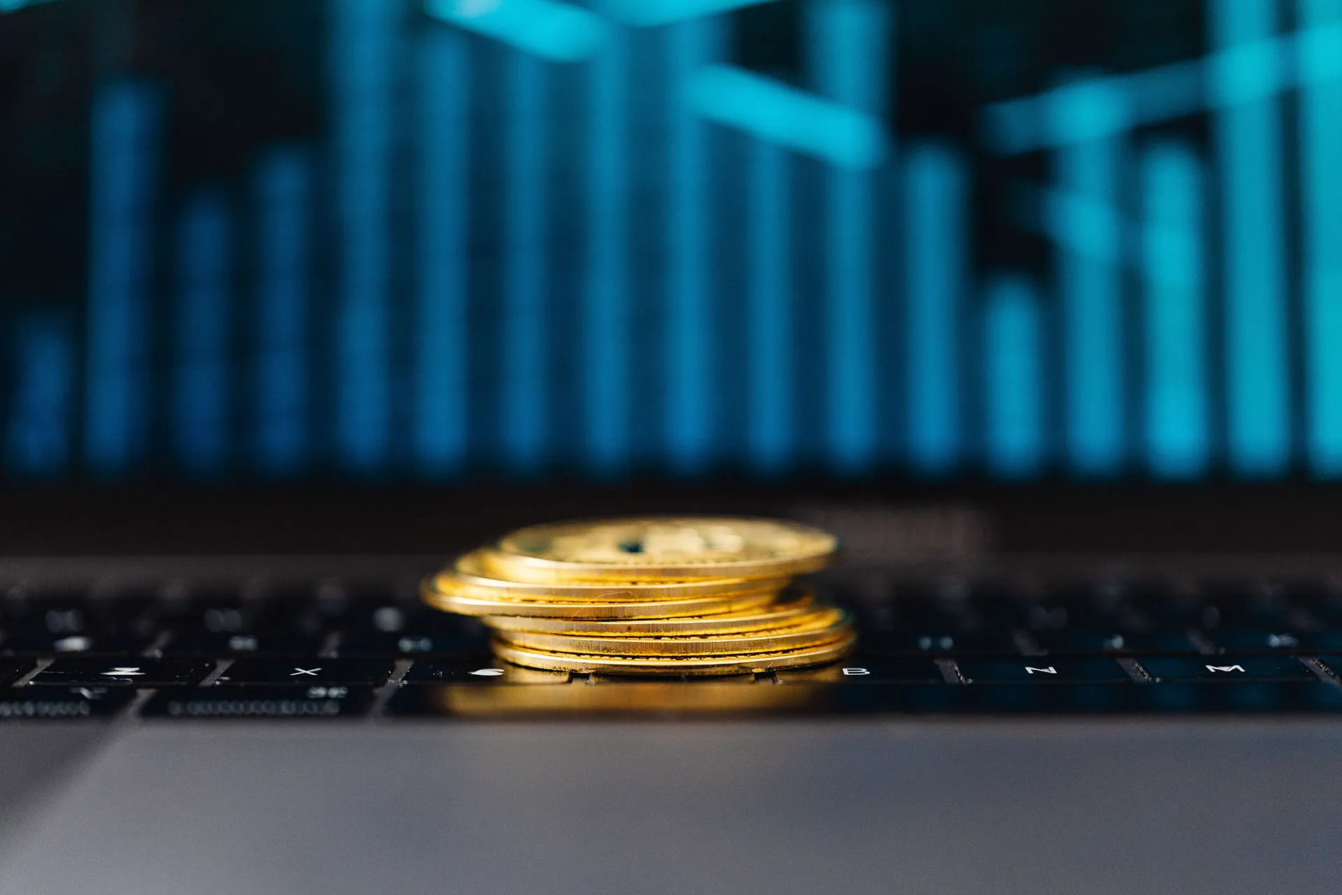  Stacks of coins in front of a laptop showing financial charts, representing interest rates, investment returns, and market growth.