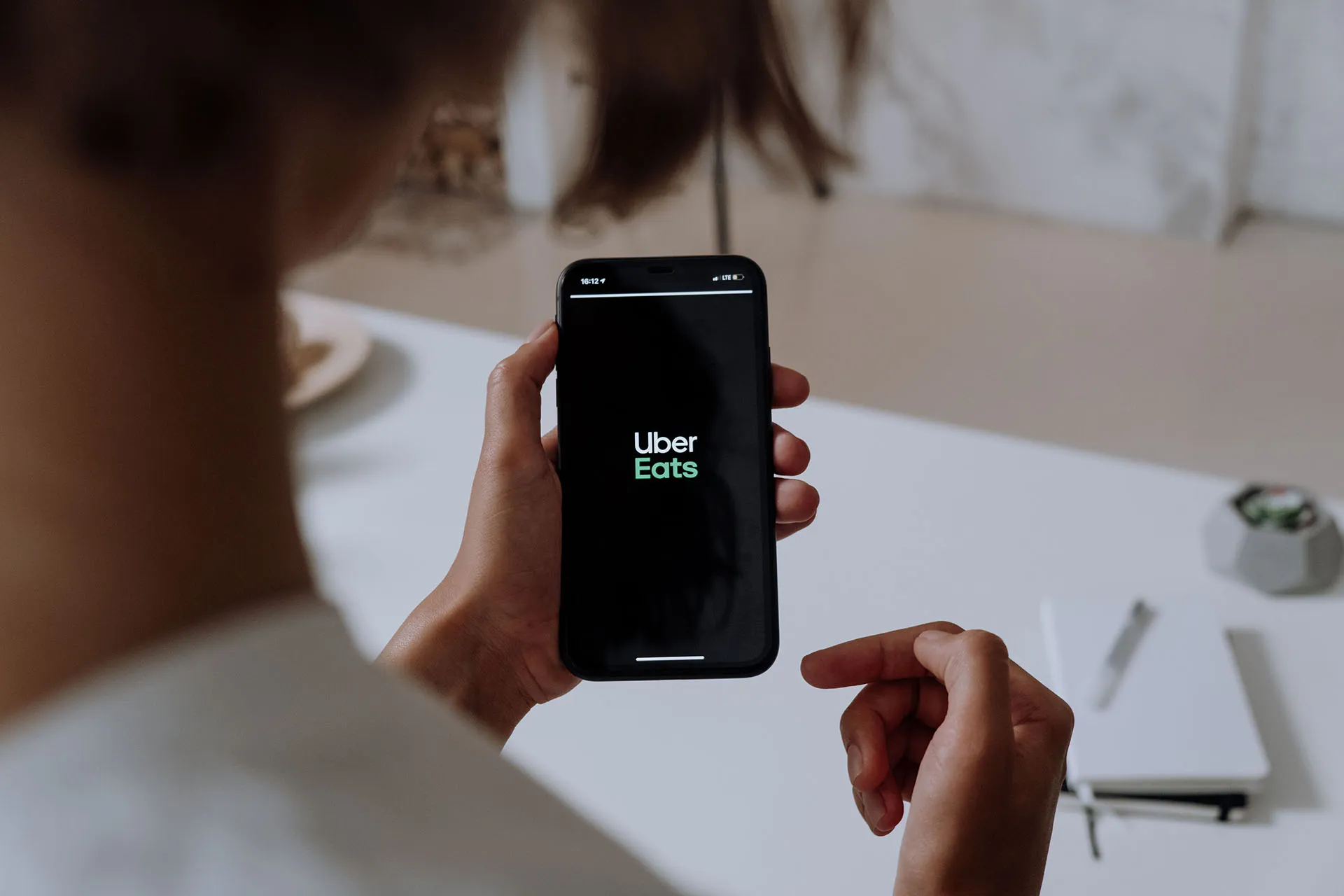  Hand holding a smartphone displaying the Uber logo on a black screen.