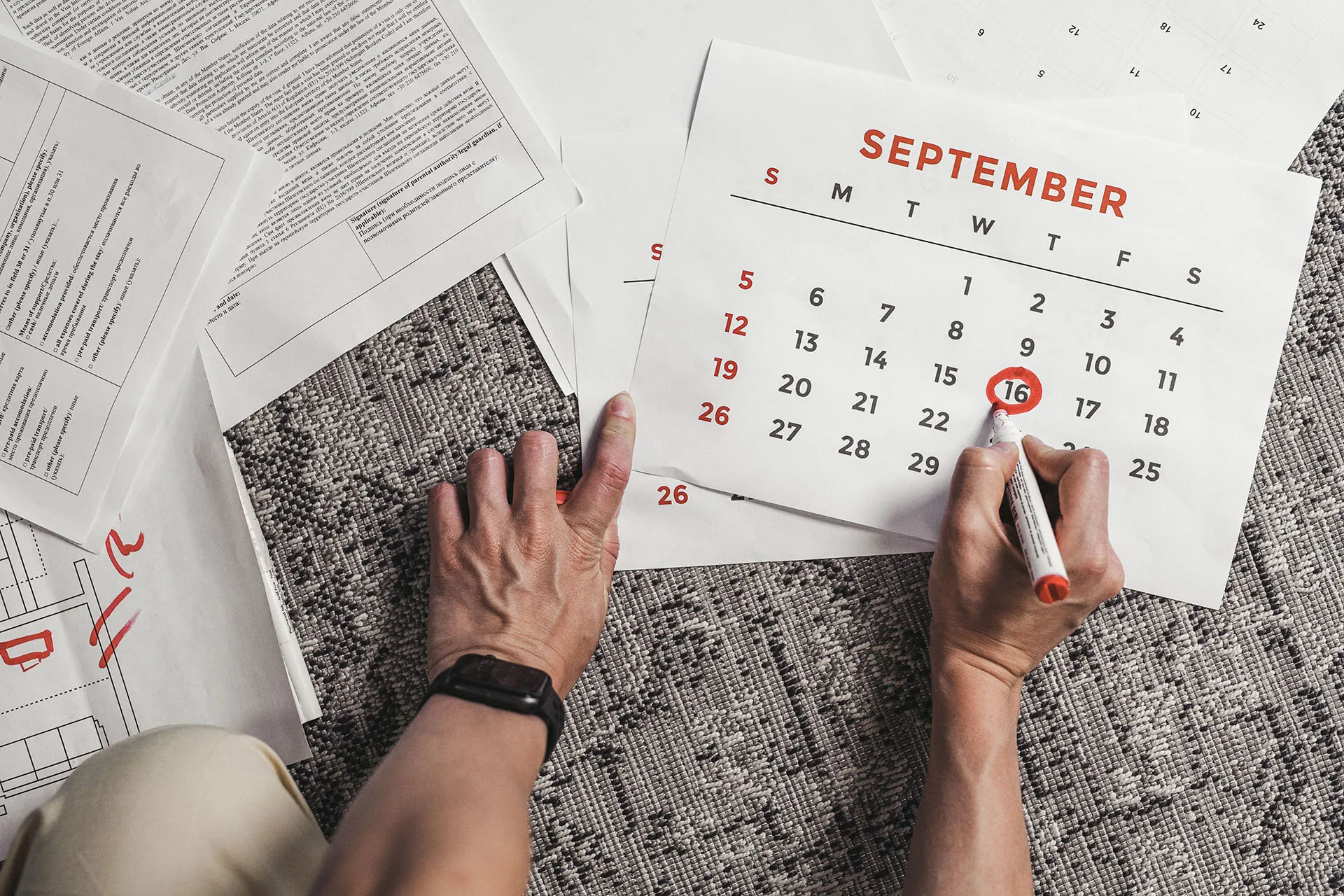 Person surrounded by papers circling a date on a calendar that says September