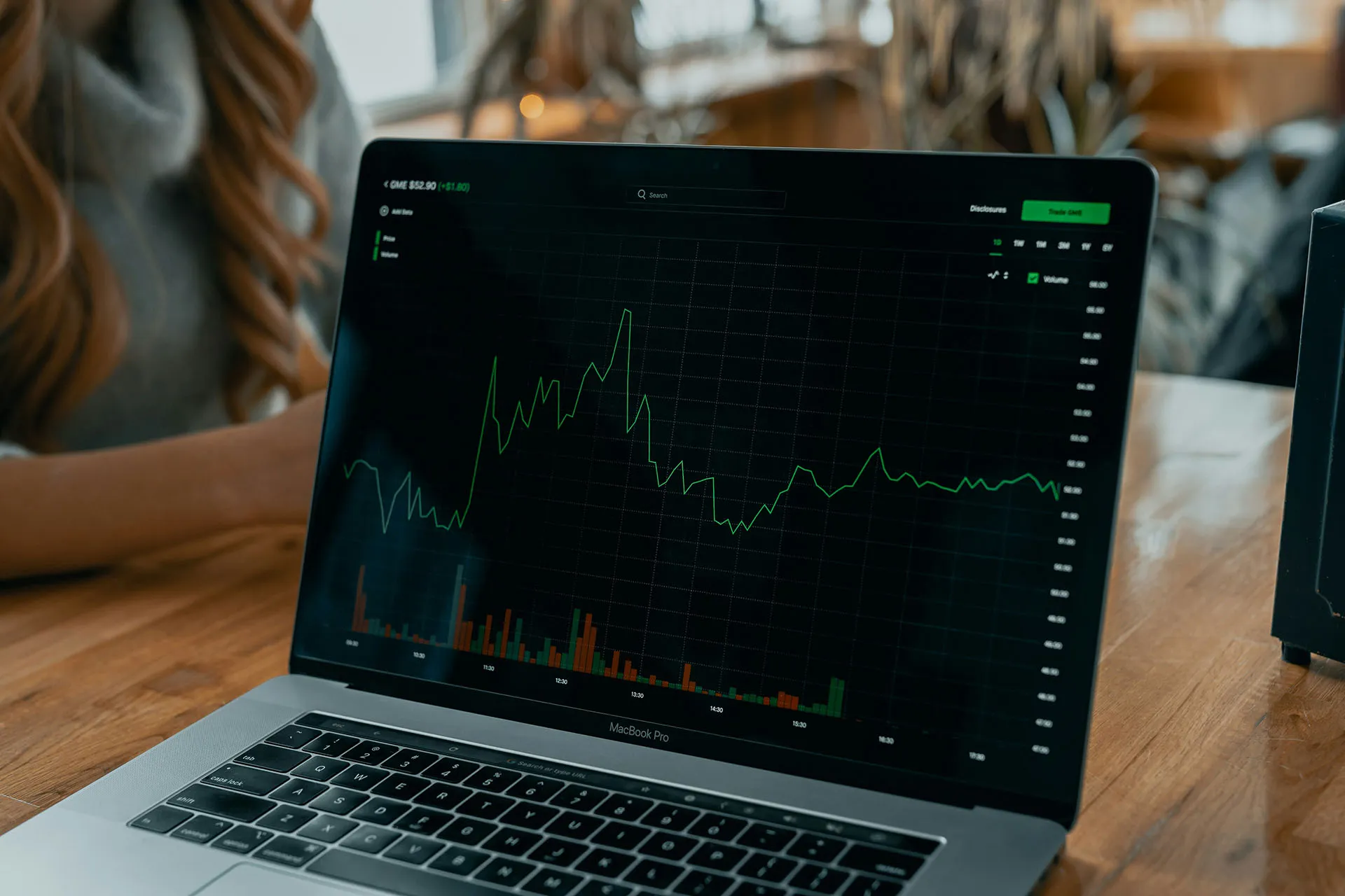  A laptop on a table displaying a fluctuating financial graph