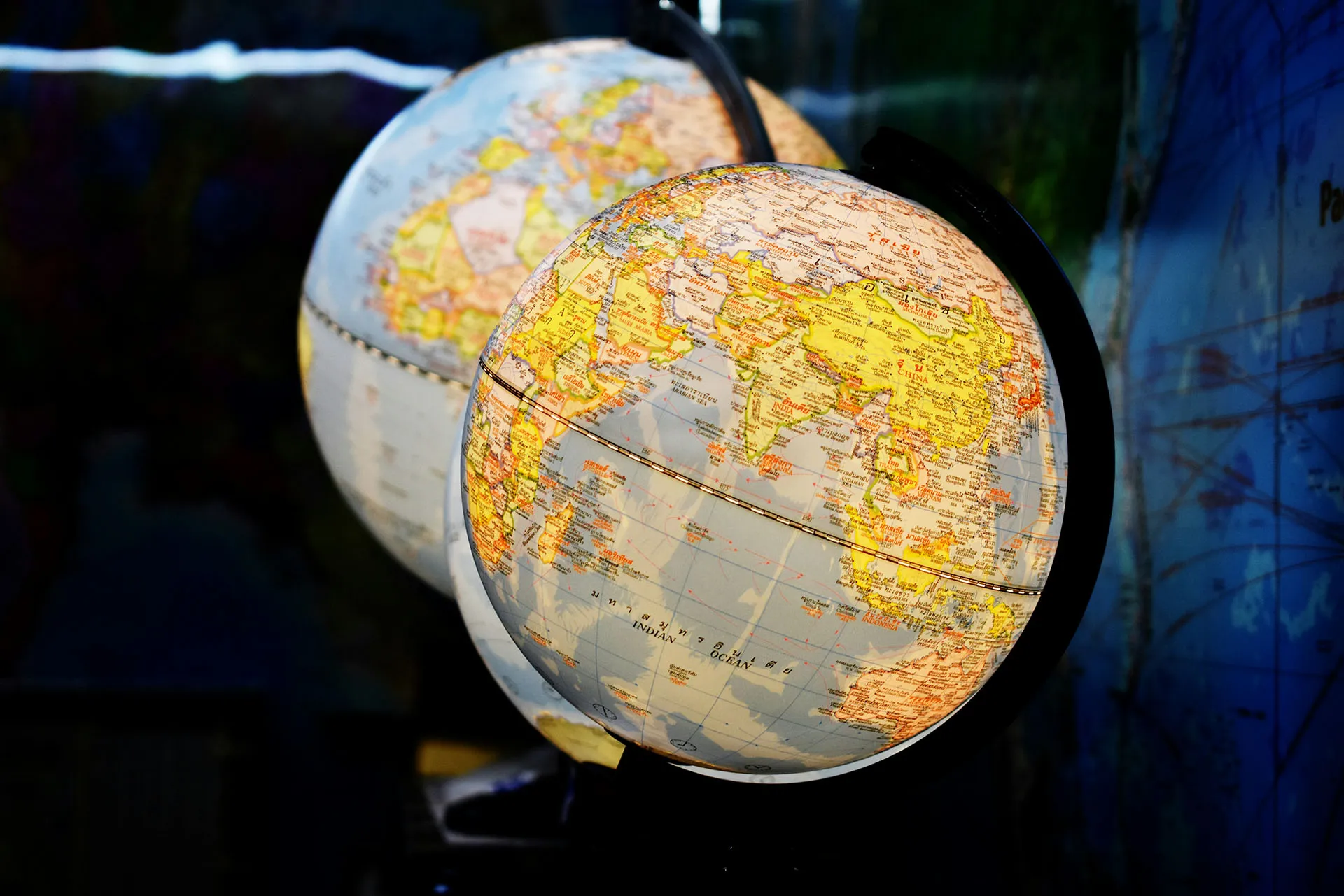  Close-up of illuminated world globes showing maps of Asia and surrounding regions in a dark display setting.