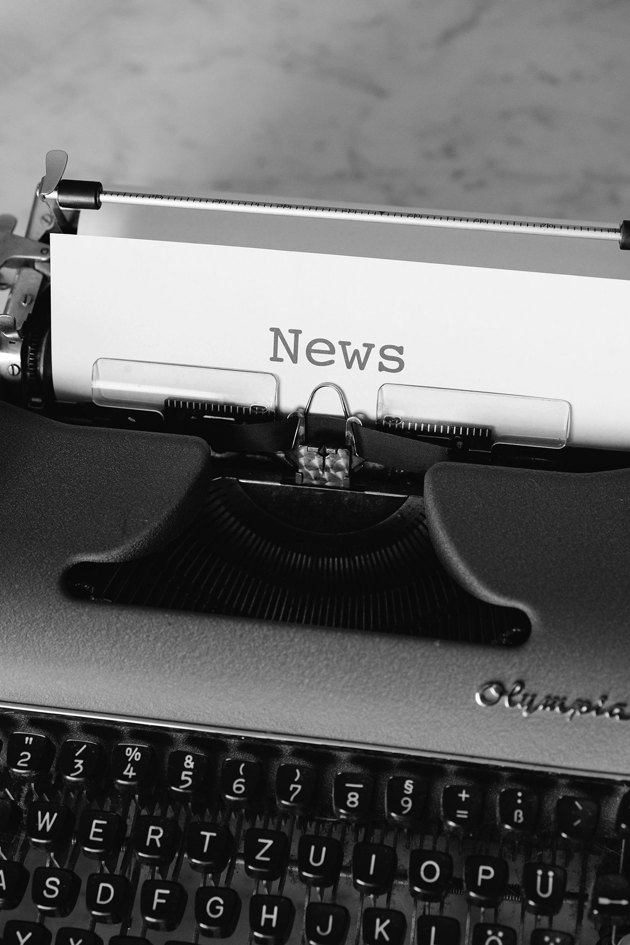 Black and white photo of a vintage typewriter with a sheet of paper displaying the word “News.”