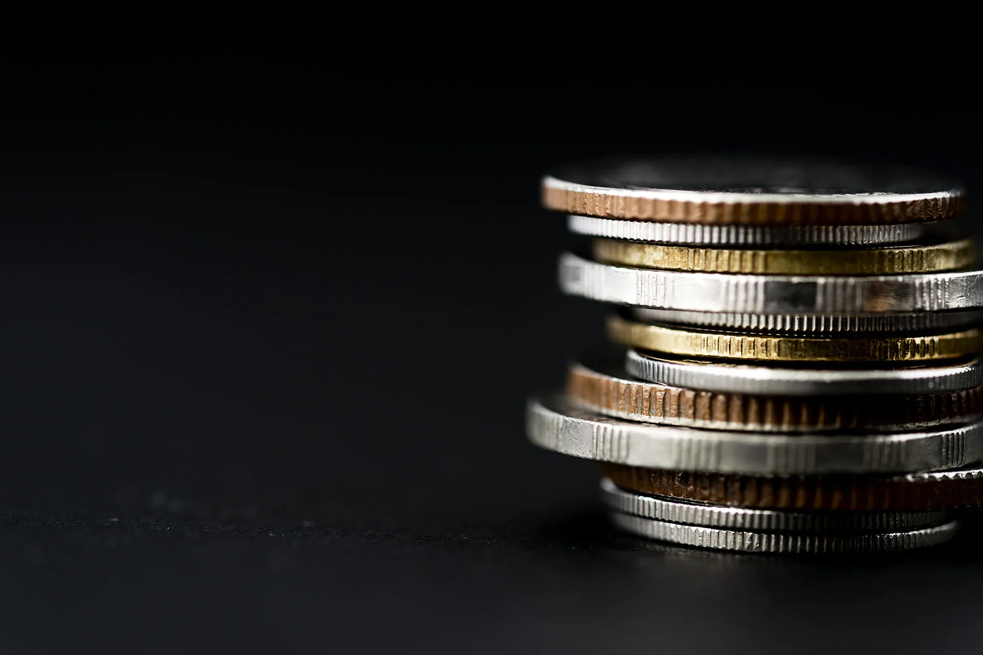 Stack of different coloured coins against a dark backdrop