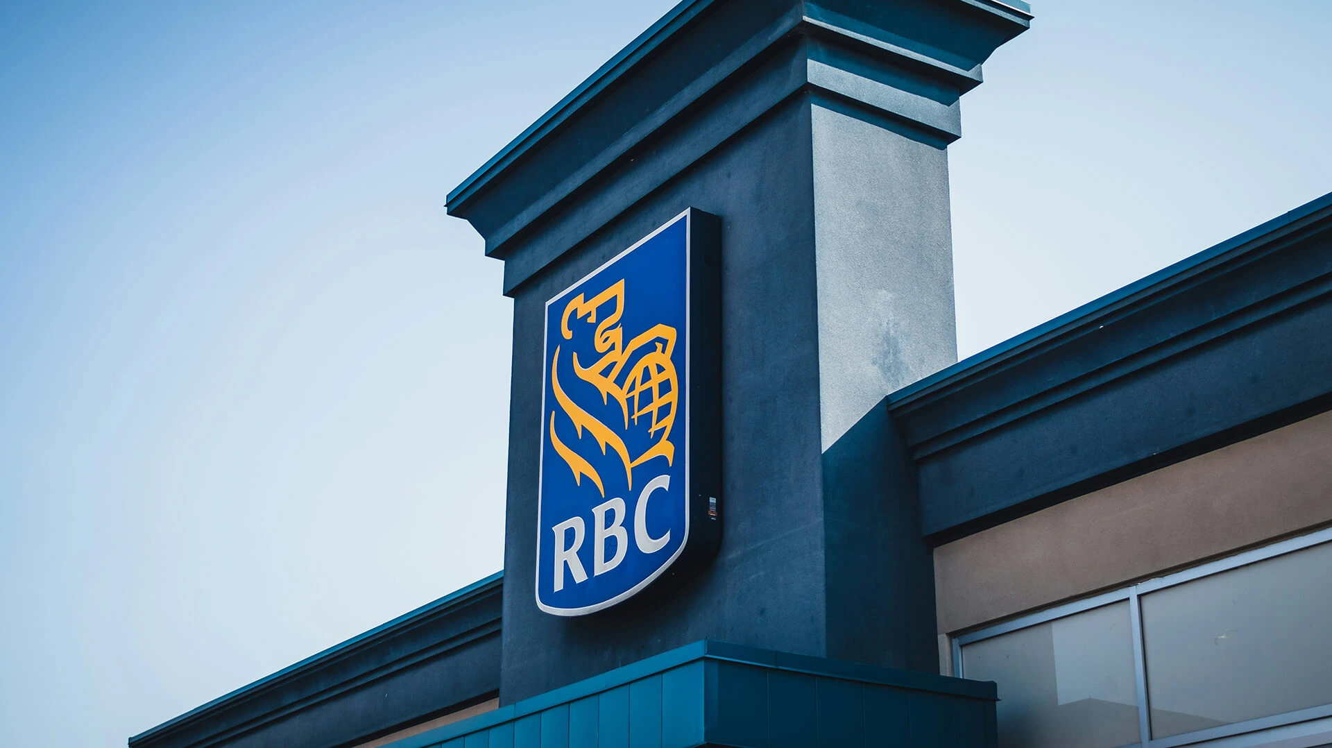 Royal Bank of Canada logo on a grey bank building against a blue sky