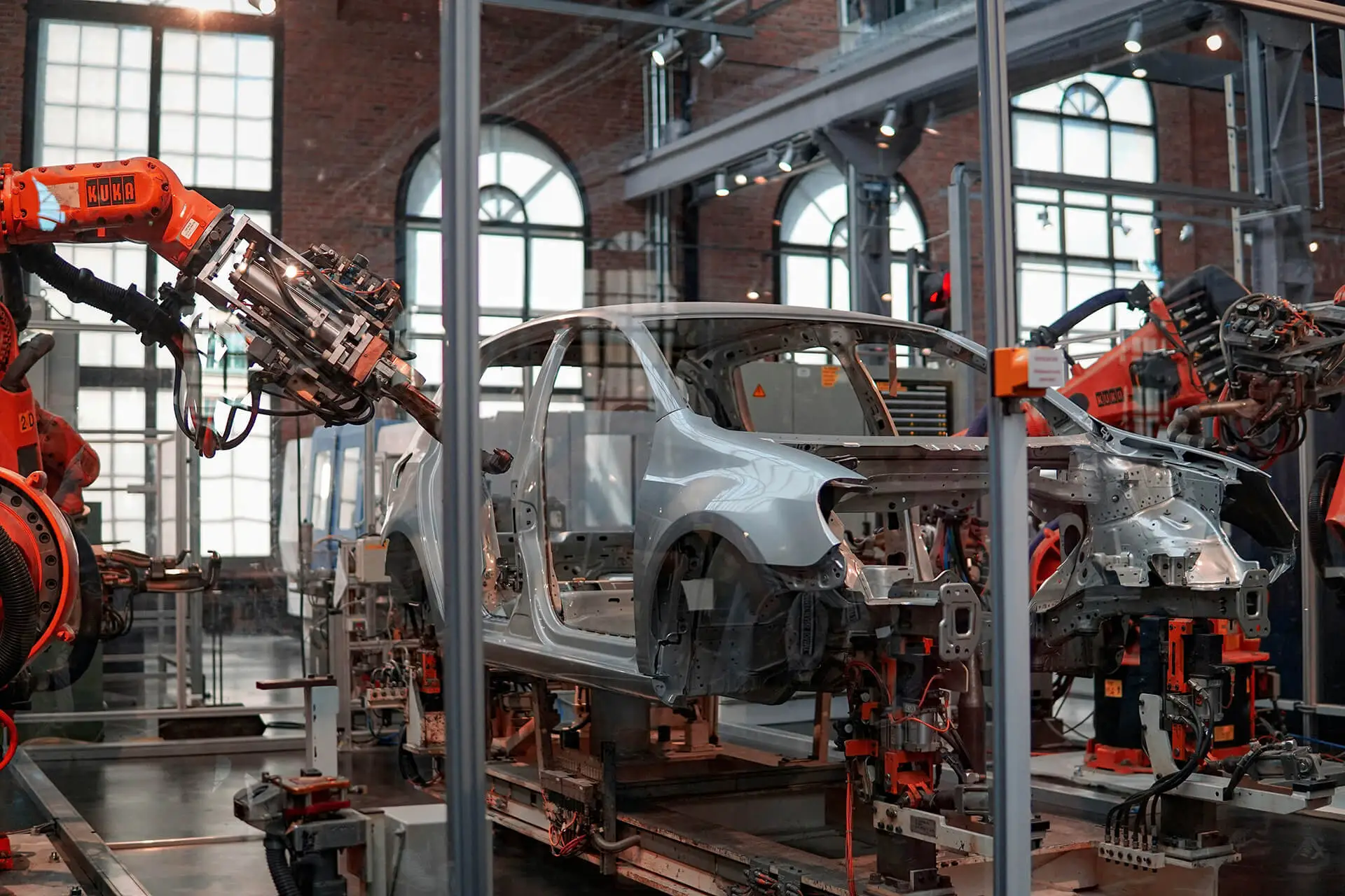Robotic arms assembling a car body frame inside an automotive manufacturing factory.