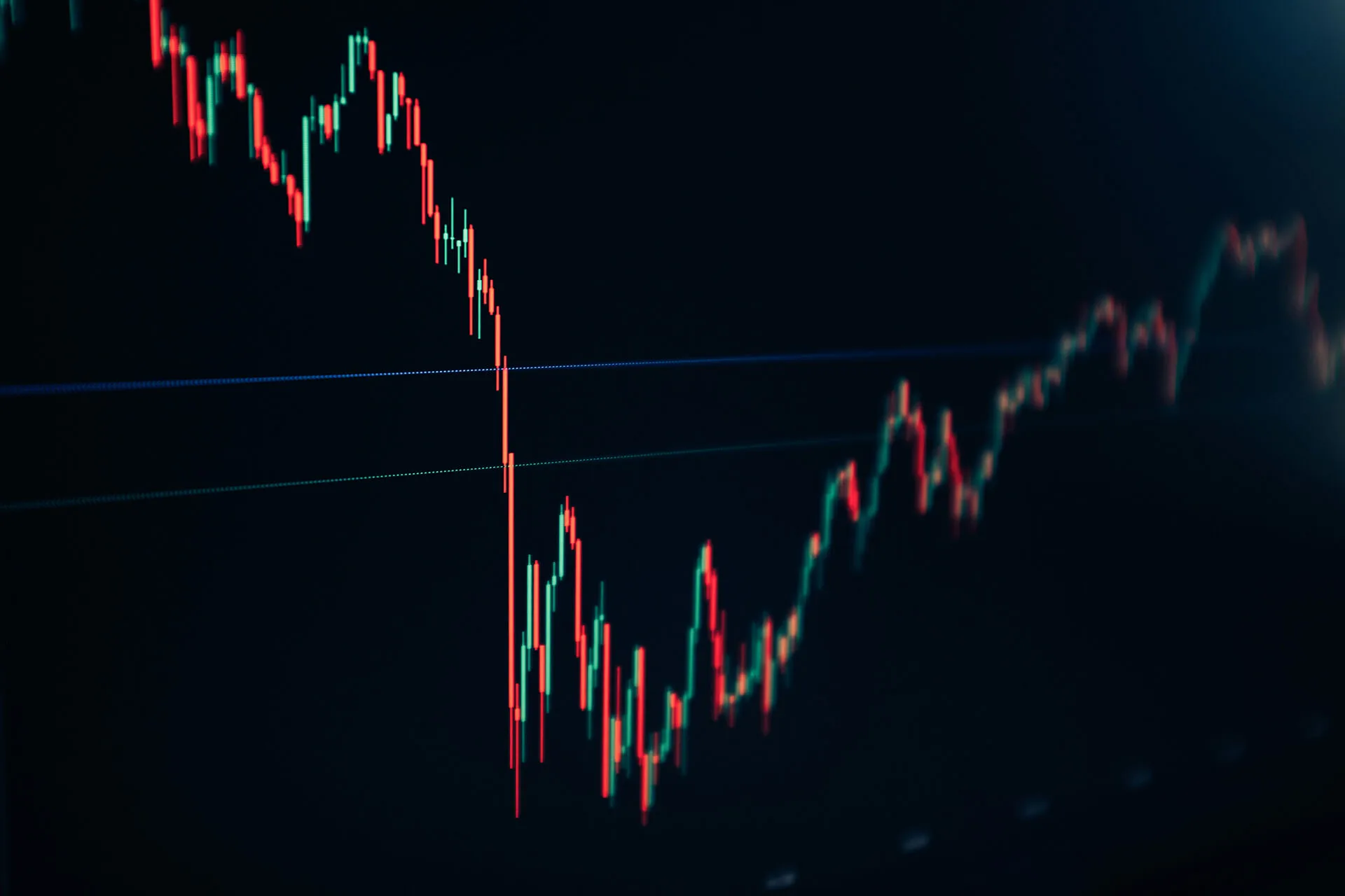 Close-up of a dark digital trading chart showing red and green candlestick price movements with a sharp drop followed by a partial recovery.